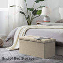 nzmegabuy beige foldable storage ottoman bench with button-tufted top placed at the end of a bed in a bedroom