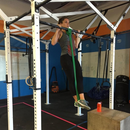 nzmegabuy athlete performing a pull-up with a green heavy-duty latex resistance band in a gym setting
