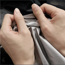 Hands holding the silver-lined interior of a black nzmegabuy water-resistant polyester hot tub cover.