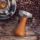 nzmegabuy stainless steel espresso coffee tamper with an ergonomic wooden handle on a background of coffee beans